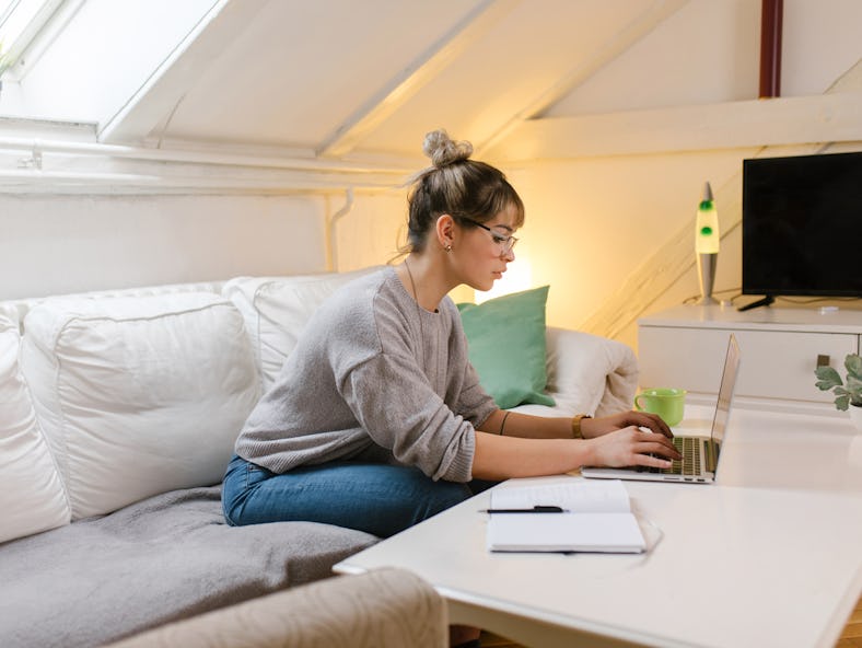 A woman using laptop and studying at home gets advice from women-owned brands sharing advice for fem...