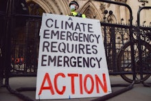 LONDON, UNITED KINGDOM - 2022/02/01: A police officer stands next to a 'Climate Emergency' placard d...