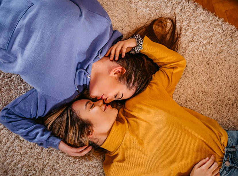 two young women laying down and cuddling as they think about how spring 2022 will be romantic for th...