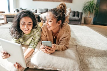 Two female students with digital tablet and cellphone at home