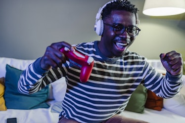 A young African-American man is at home on the couch, he is having fun playing video games