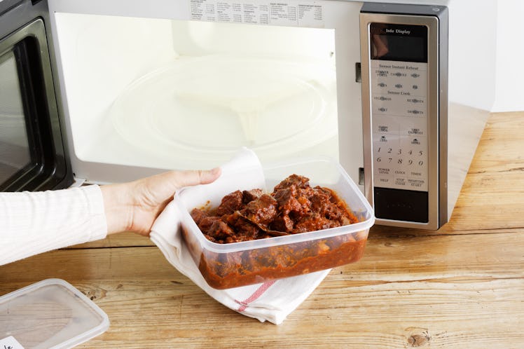woman heating leftovers in a microwave 