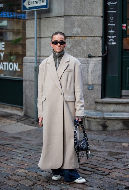 COPENHAGEN, DENMARK - FEBRUARY 02: A guest is seen wearing zipper, creme white coat, black Balenciag...