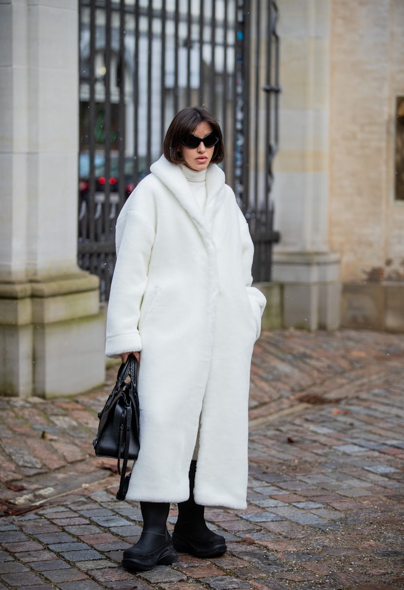 COPENHAGEN, DENMARK - FEBRUARY 02: A guest is seen wearing white wool coat, black bag, boots outside...