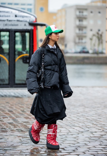 COPENHAGEN, DENMARK - FEBRUARY 01: A guest is seen wearing cap, black down feather jacket, skirt, re...
