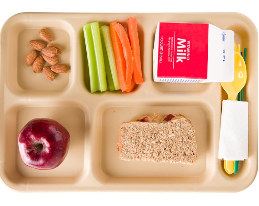 An overhead close up of a tray containing a healthy school lunch. It consists of crunchy peanut butt...