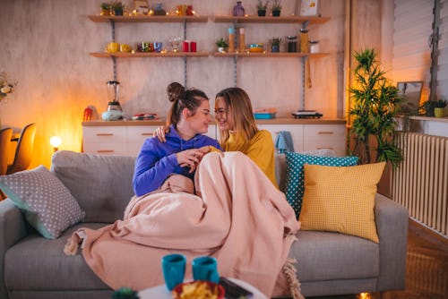 Young lesbian couple share cuddling on the couch at home. These zodiac signs will be least affected ...