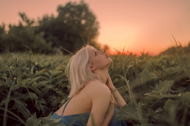 Young woman looking up at the sunset in the sky, thinking about her zodiac sign's February 14, 2022 ...
