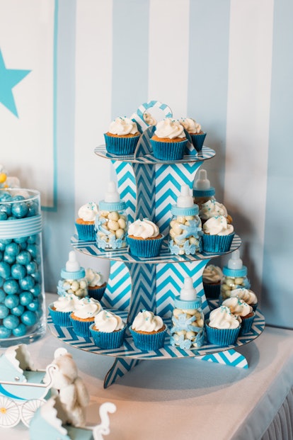 Blue cupcake stand with sweets and baby bottles on a gender reveal party or a baby shower