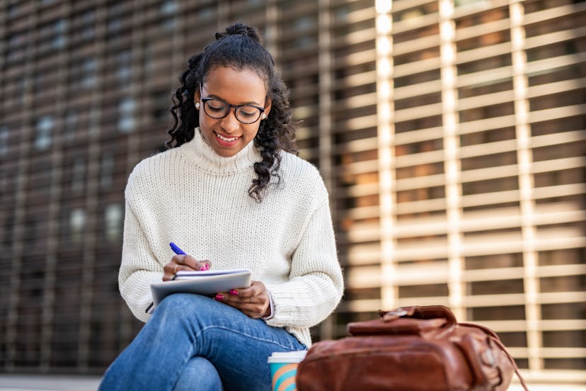 It's all easier when done digitally. A young black woman sits on a bench and writes down her daily o...