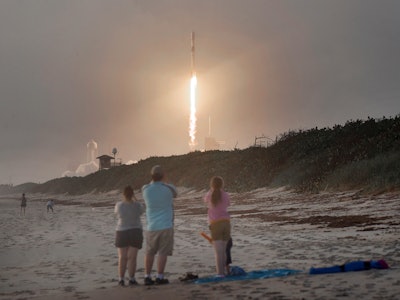 Spectators watch from Canaveral National Seashore as a SpaceX Falcon 9 rocket carrying 60 Starlink s...