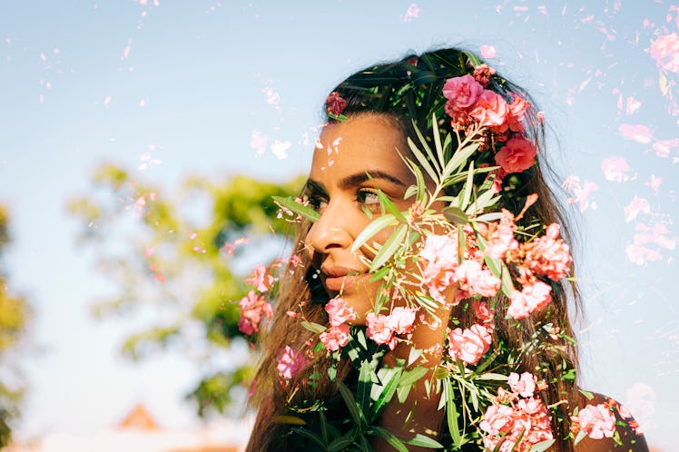 Young woman surrounded by flowers, knowing her lucky zodiac sign will have the best week of February...