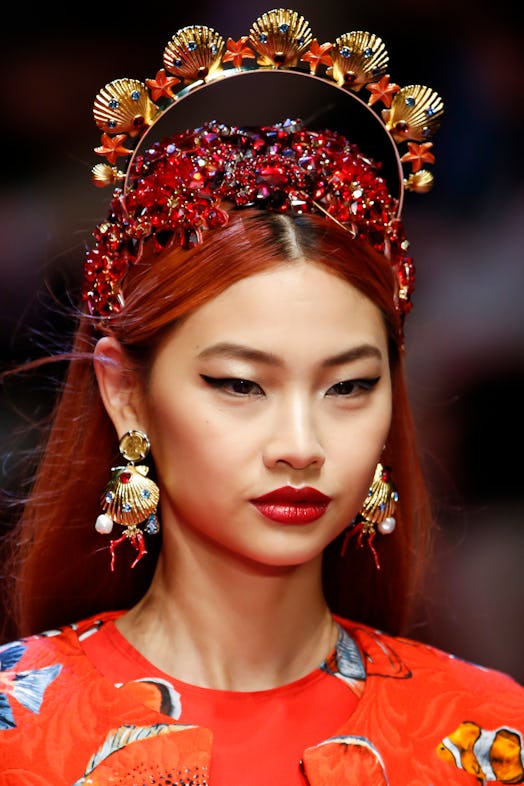 A model walks the runway wearing large earrings and a jeweled headpiece at Dolce and Gabbana's show ...