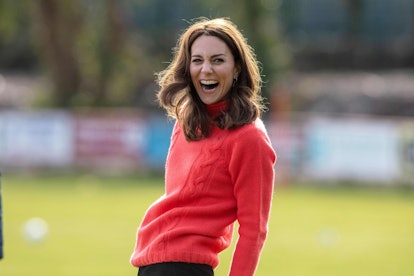 Kate Middleton laughing and wearing a red, cable knit sweater in Galway in 2020. 