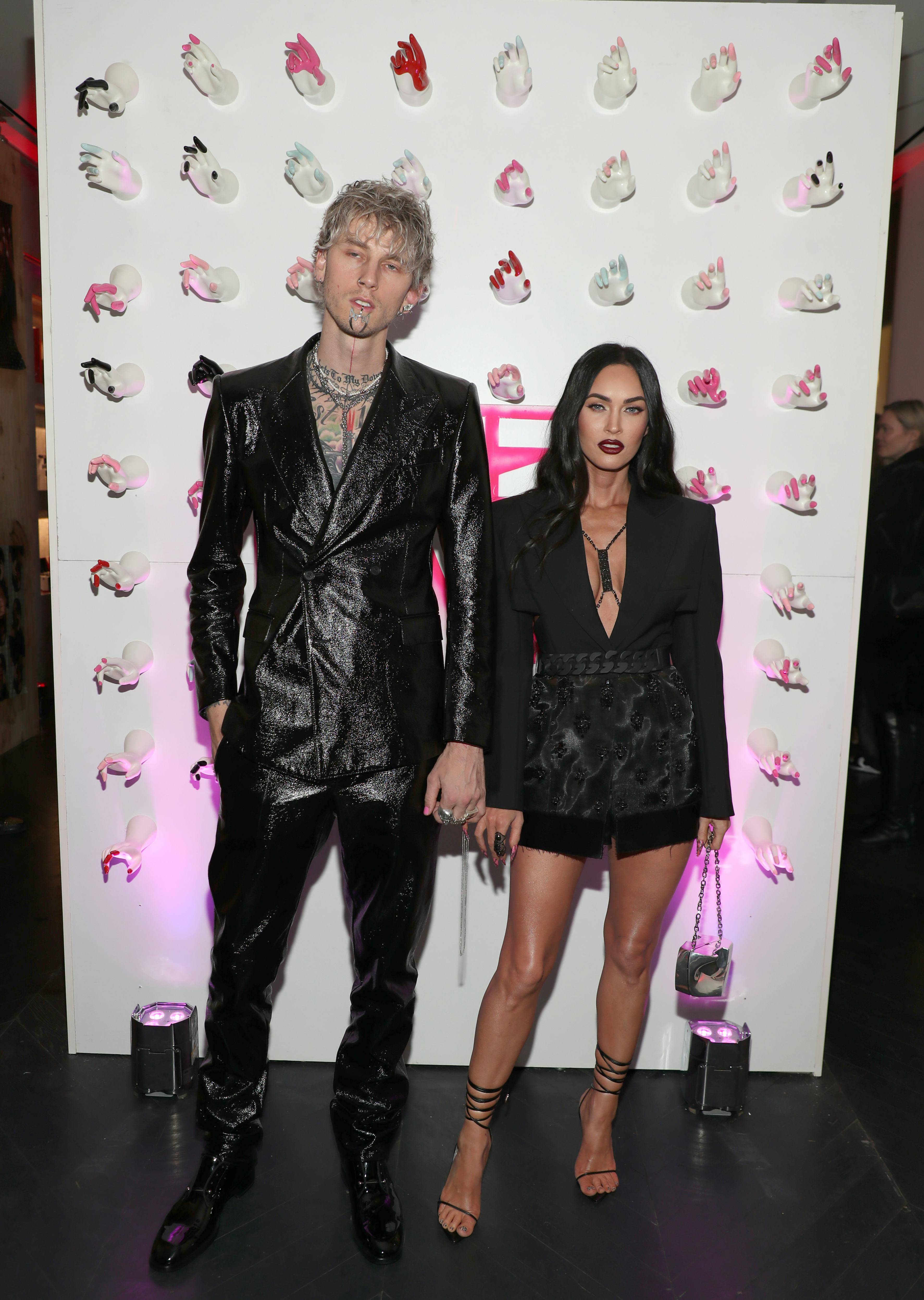Megan Fox in a short, black blazer and Machine Gun Kelly in a black suit.