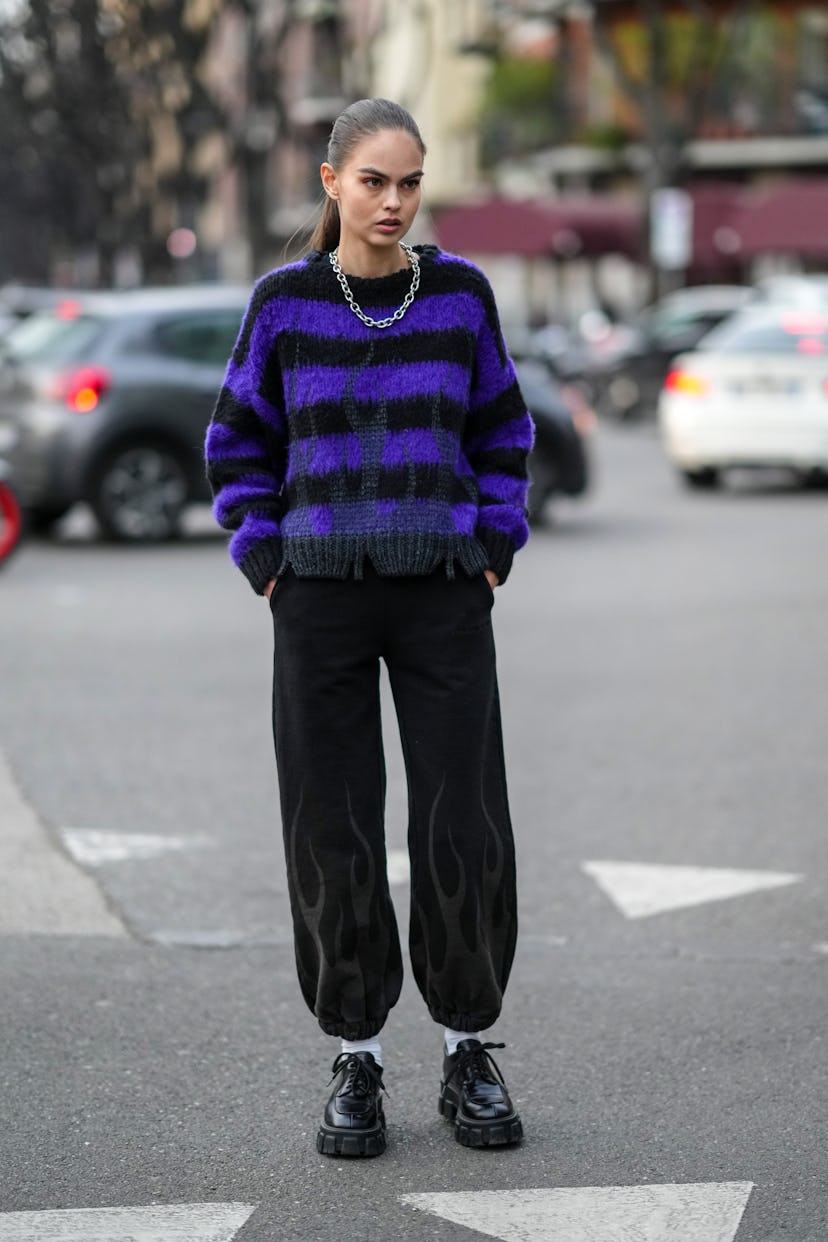 MILAN, ITALY - FEBRUARY 24: A guest wears a large silver chain necklace, a neon purple and black str...