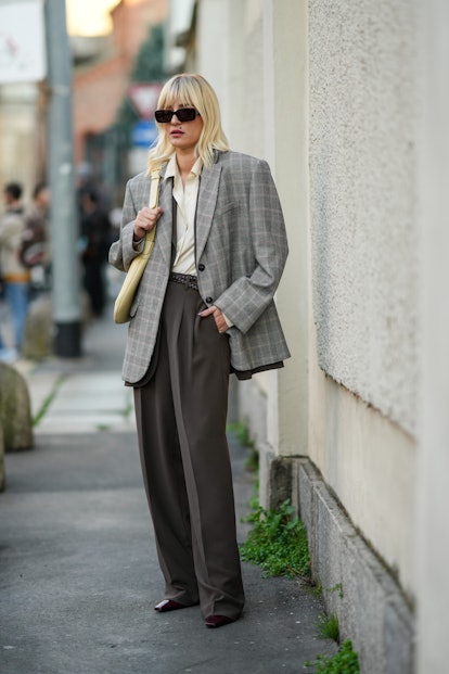 MILAN, ITALY - FEBRUARY 23: Eleonora Carisi wears black sunglasses, a white latte silk shirt, a dark...
