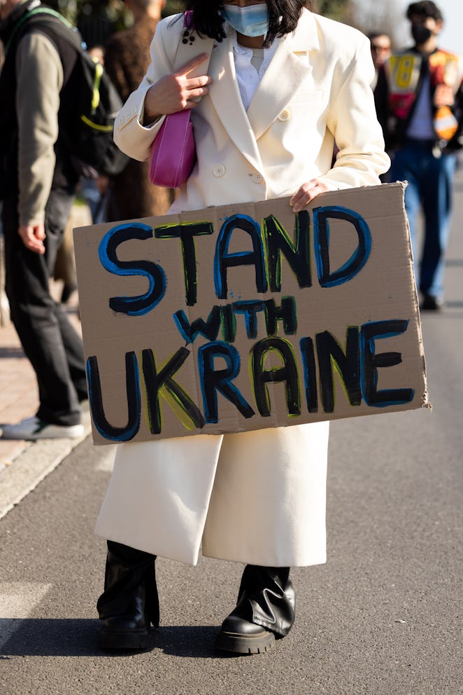 MILAN, ITALY - FEBRUARY 25: A girl poses with a protest sign "No World War III" and "Stand with Ukra...