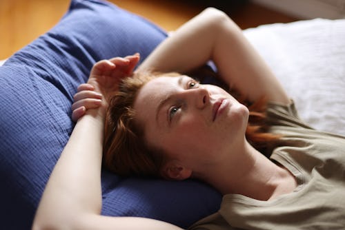 A woman lies down on a blue pillow. Here's your daily horoscope for March 1, 2022.