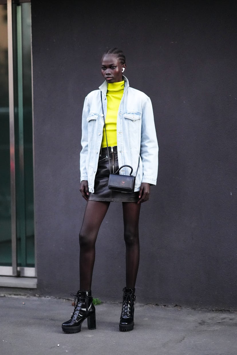 MILAN, ITALY - FEBRUARY 26: A model wears a neon yellow ribbed wool turtleneck pullover, a white blu...