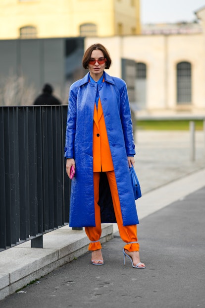MILAN, ITALY - FEBRUARY 24: A guest wears orange sunglasses, a royal blue electric shirt, a royal bl...