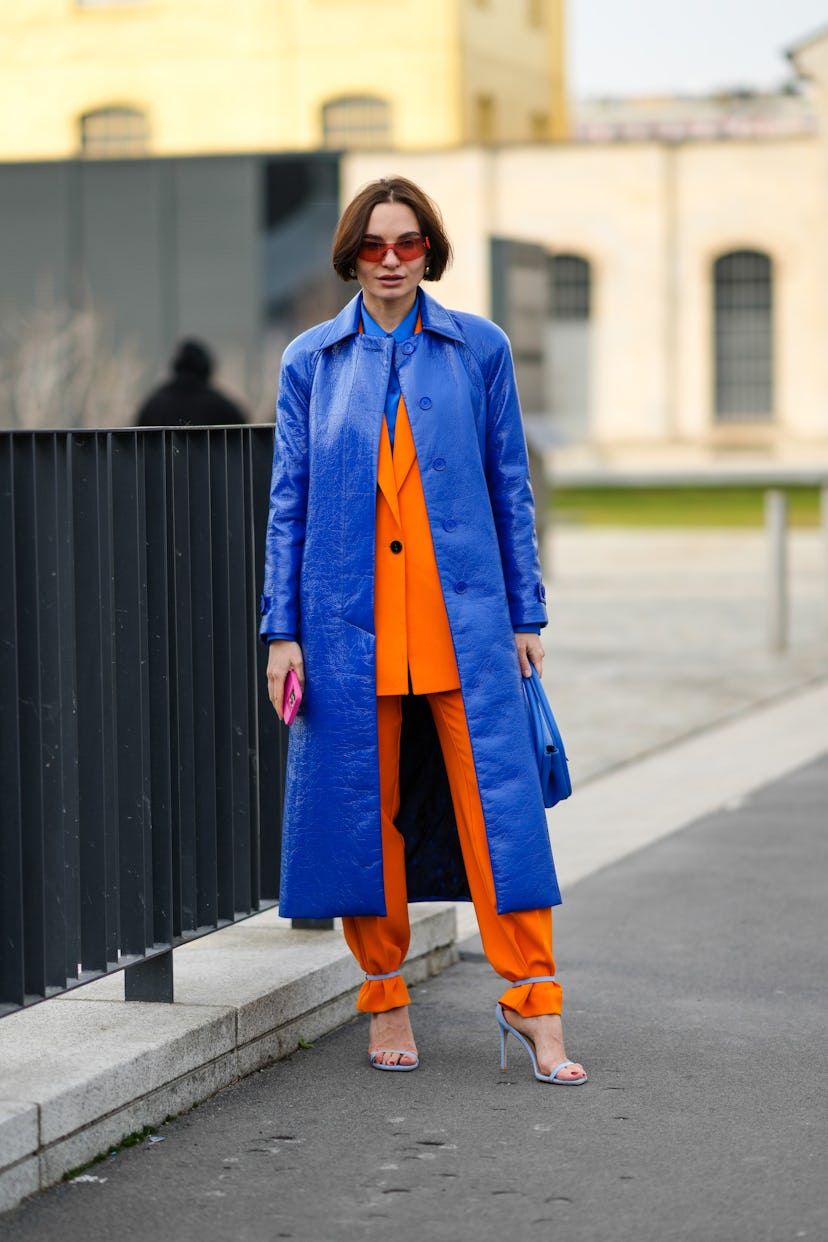 MILAN, ITALY - FEBRUARY 24: A guest wears orange sunglasses, a royal blue electric shirt, a royal bl...