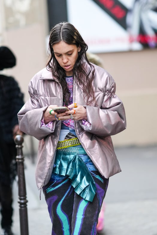PARIS, FRANCE - FEBRUARY 28: A guest wears a purple / pink / black print pattern t-shirt, a silver p...