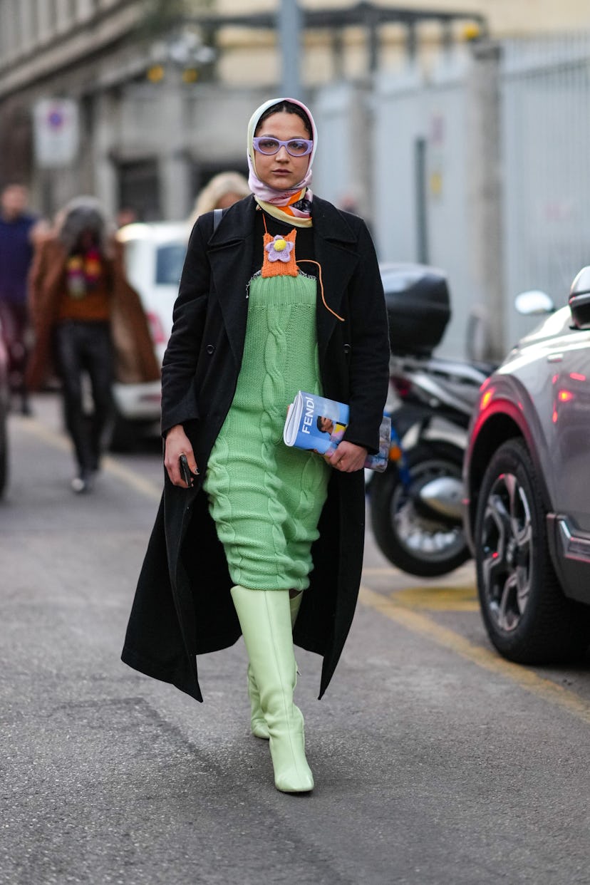 MILAN, ITALY - FEBRUARY 23: A guest wears a pale pink / green / orange print pattern silk scarf, pur...