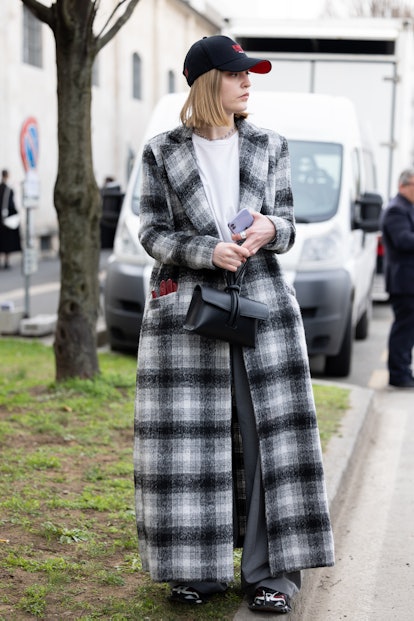 MILAN, ITALY - FEBRUARY 24: A guest is seen ahead of the Prada fashion show wearing a long checkered...