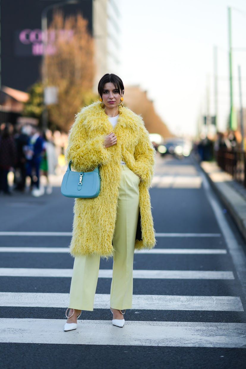 MILAN, ITALY - FEBRUARY 25: Katie Giorgadze wears yellow pendants earrings, a white pullover, a yell...