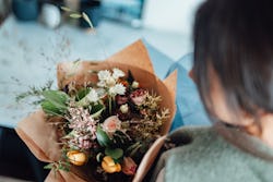 High angle view of young woman holding fresh flower bouquet. Valentine’s Day. Flower delivery.