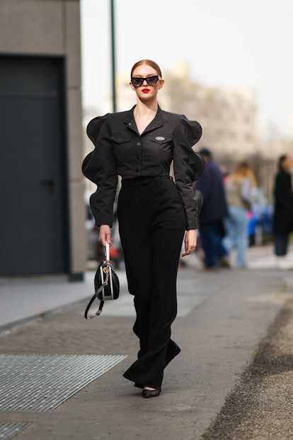 MILAN, ITALY - FEBRUARY 24: Larsen Thompson wears black sunglasses, a black shirt with puffy sleeves...