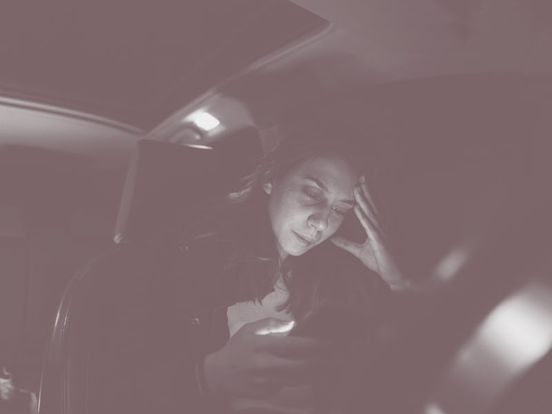 Worried and abused Caucasian teenage girl, sitting in the car and using mobile phone