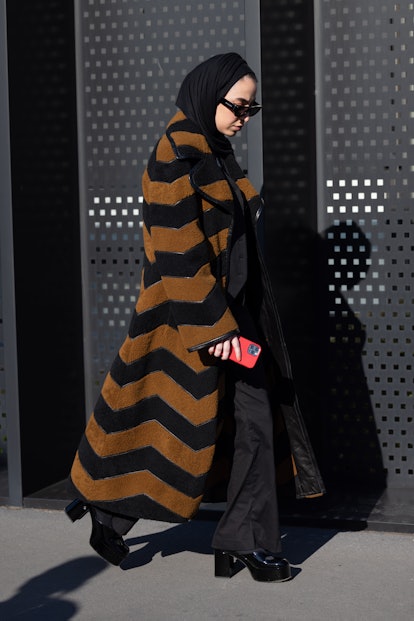MILAN, ITALY - FEBRUARY 25: A guest is seen ahead of the Gucci fashion show wearing a striped coat d...