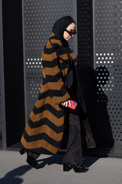 MILAN, ITALY - FEBRUARY 25: A guest is seen ahead of the Gucci fashion show wearing a striped coat d...