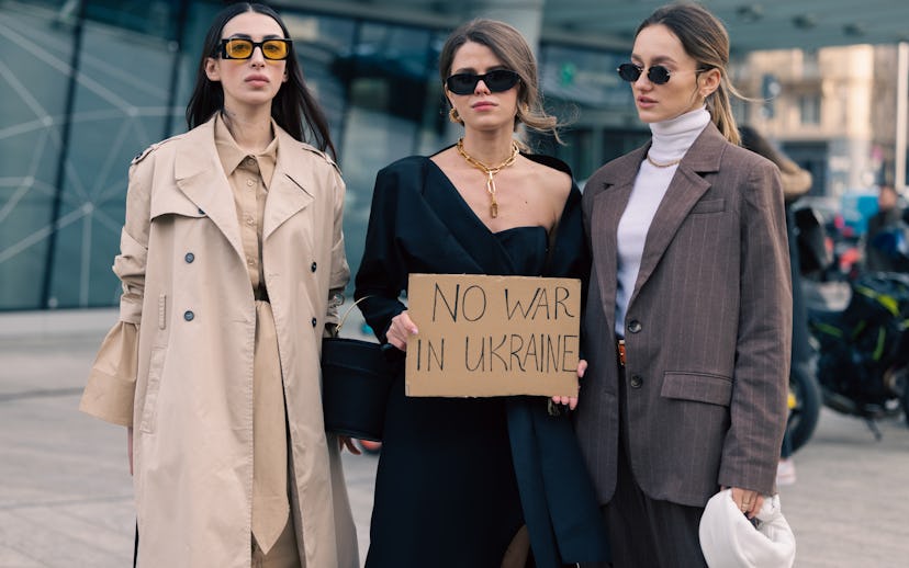 MILAN, ITALY - FEBRUARY 24: Three guests pose ahead of the Max Mara fashion show with a sign against...