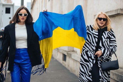 MILAN, ITALY - FEBRUARY 24: Two guests hold a Ukrainian flag outside the Prada show at Fondazione Pr...