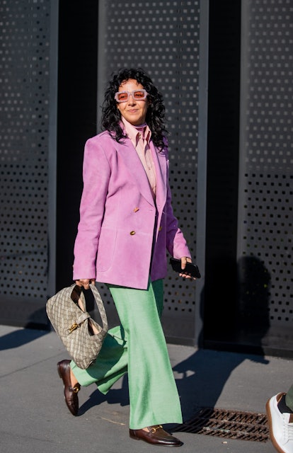 MILAN, ITALY - FEBRUARY 25: A guest is seen wearing pink blazer, green pants, bag, loafers outside G...