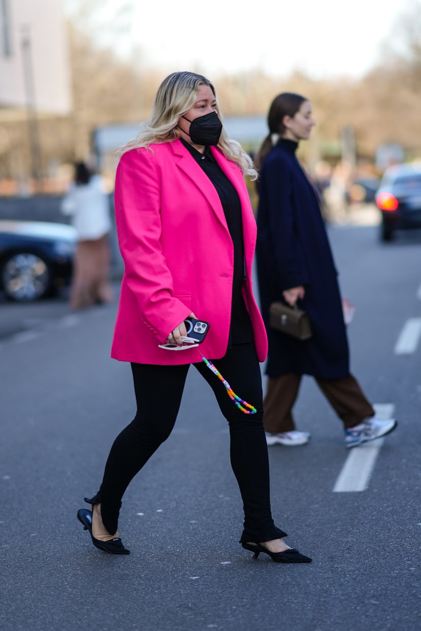 MILAN, ITALY - FEBRUARY 26: A guest wears a black shirt, a neon pink blazer jacket, black slit /spli...