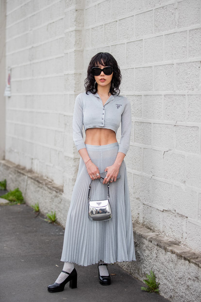 MILAN, ITALY - FEBRUARY 24: Xiayan Guo seen wearing grey cropped top, silver bag, pleated skirt, hee...