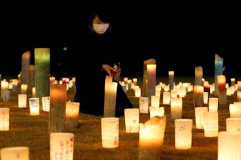 A woman lights candles for victims of the 2011 Great East Japan earthquake and tsunami in Futaba, Fu...