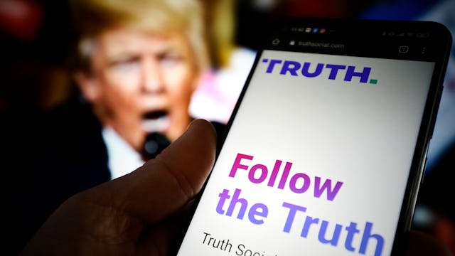 The TRUTH Social website is seen on a mobile device with an image of former US president Donald Trum...