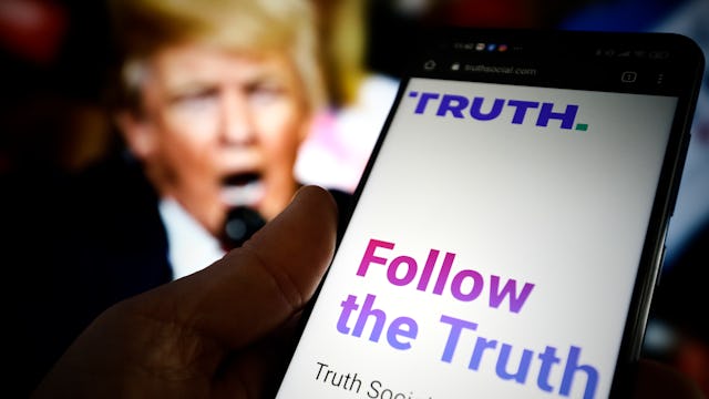 The TRUTH Social website is seen on a mobile device with an image of former US president Donald Trum...