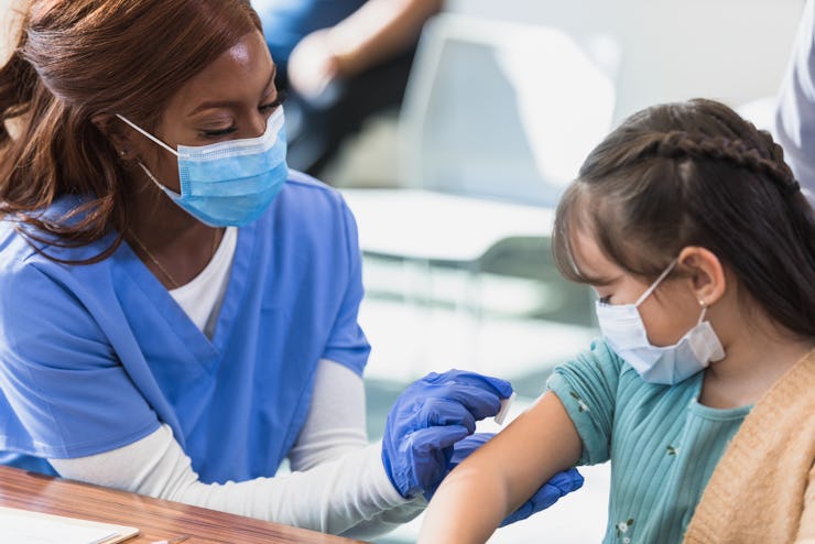 The young patient watches the nurse as she prepares the injection site.
