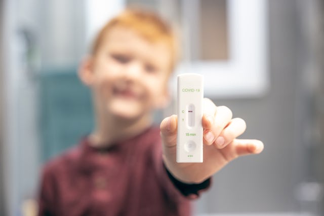 Close-up of a young child showing the negative result of a Covid-19 test onto the lateral flow test ...