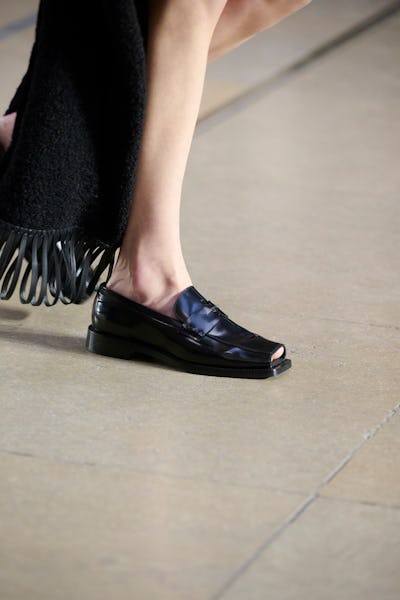 a model wearing black peep-toe loafers on the Louis Vuitton runway