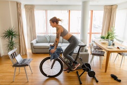 A tattooed woman rides a stationary bike. Here's your daily horoscope for March 14, 2022.