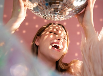Young woman laughing under a disco ball, knowing the week of March 21, 2022 will be the best for her...