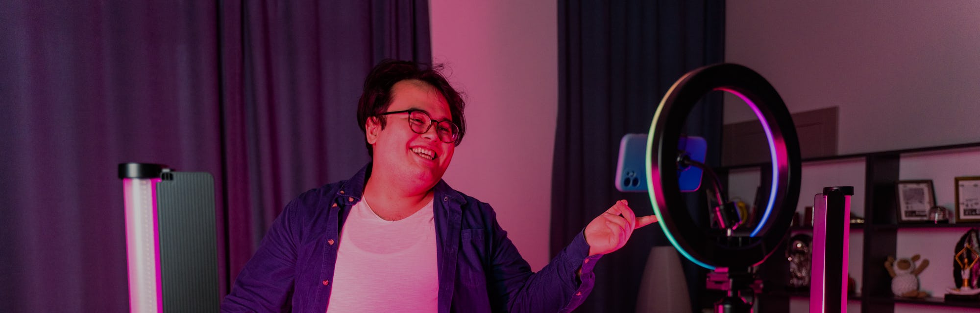 overweight young man filming videos at home and talking to camera set on ring light