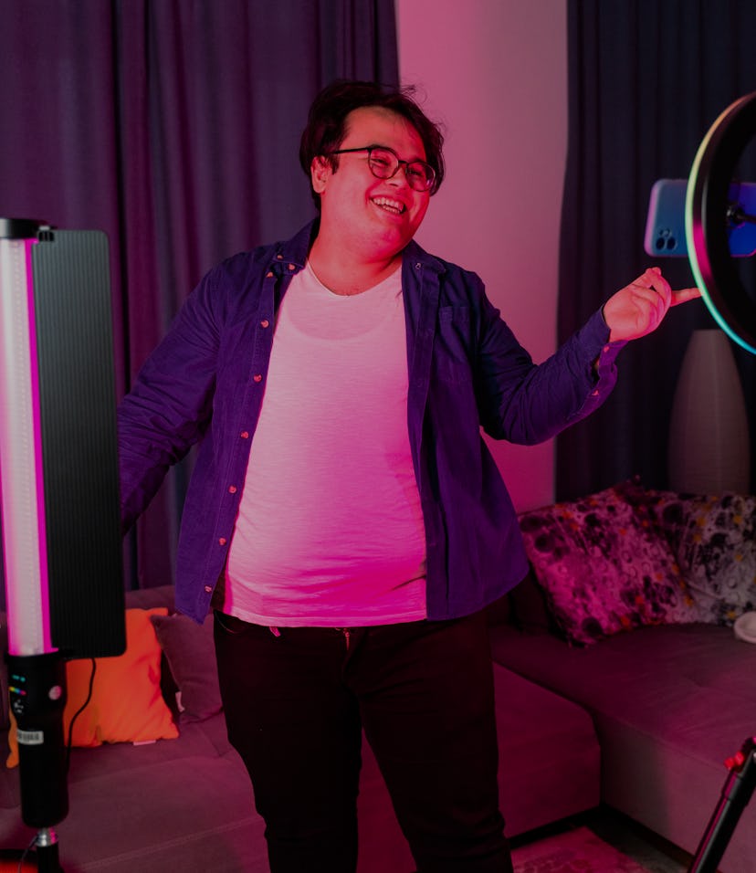 overweight young man filming videos at home and talking to camera set on ring light